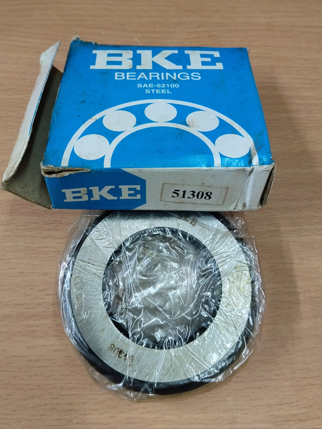 A BKE Bearings steel bearing, model 51308, shown with its original blue cardboard packaging box on a light wood tabletop.