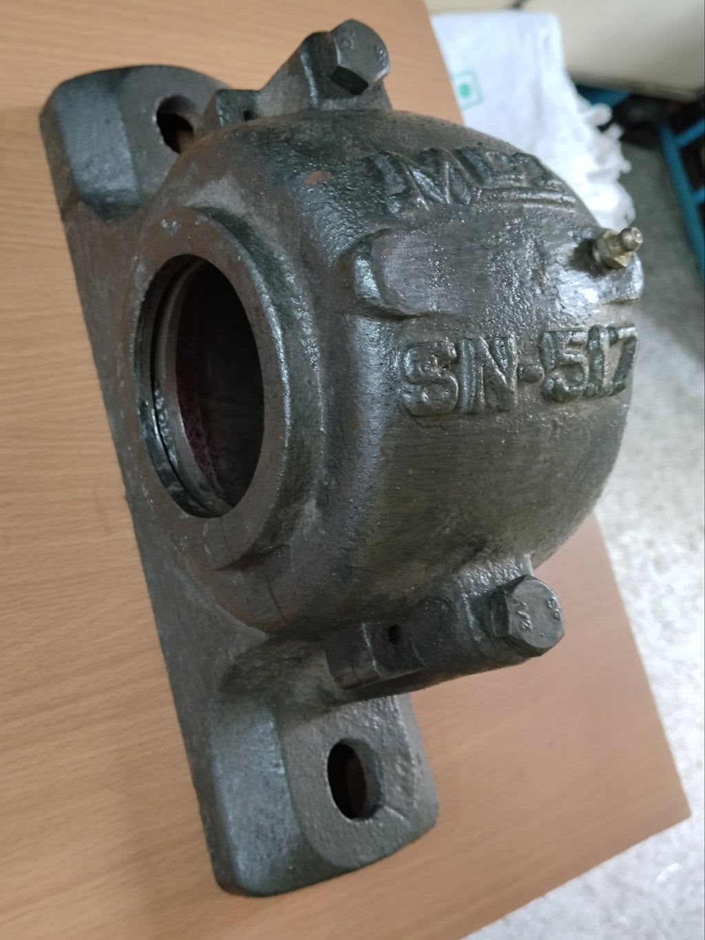 A cast iron PLUMMER BLOCK with stamped text 'SN-517' and 'MIL' on a light wood tabletop.